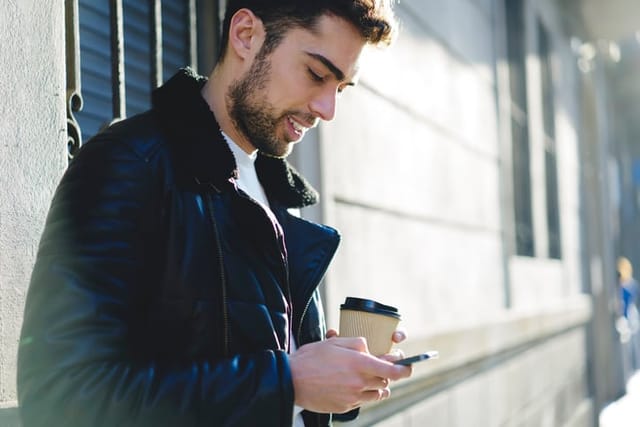 Young man on phone standing outdoors.