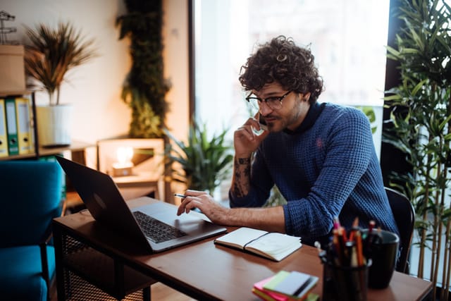 Young man talking on the phone in his home office.