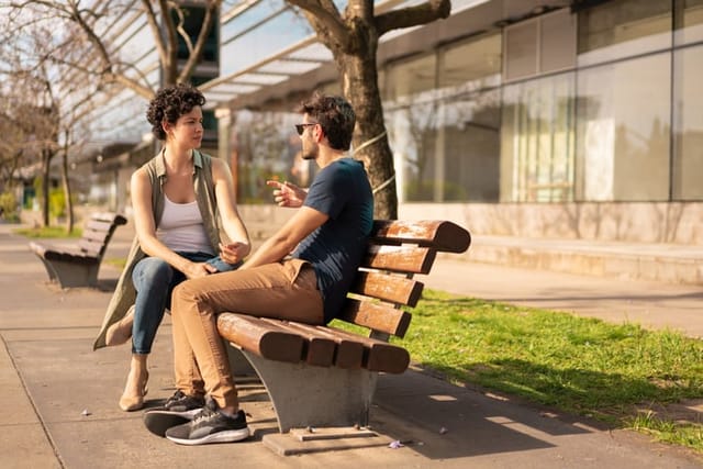 Friends talking together on a park bench.