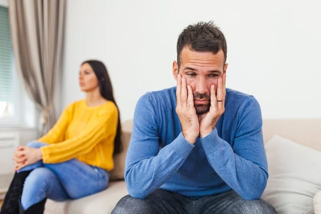 Couple sitting on the couch not speaking.