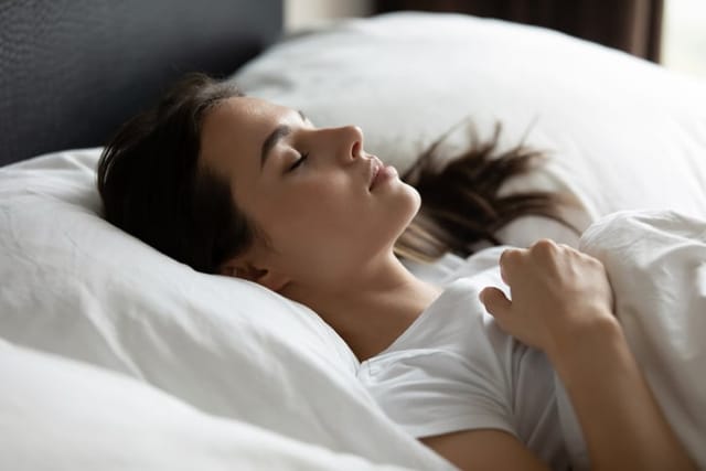 Woman lying comfy in bed asleep.
