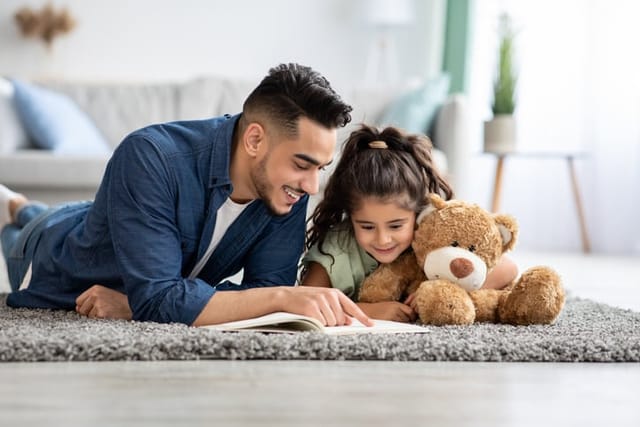 Dad reading a book to his daughter at home.