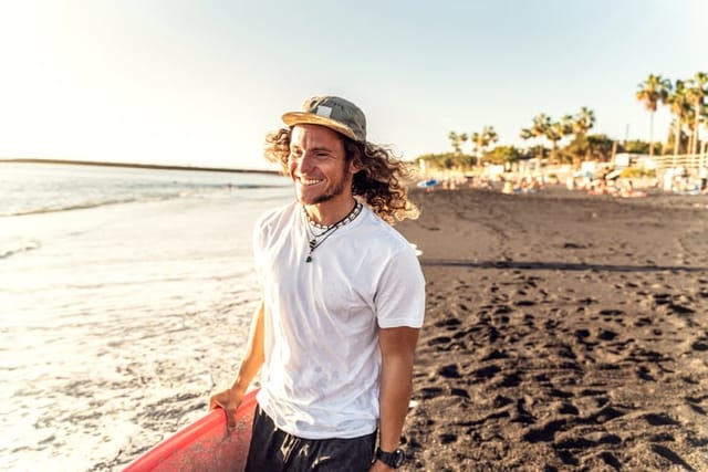 Man walking with surfboard on the beach.