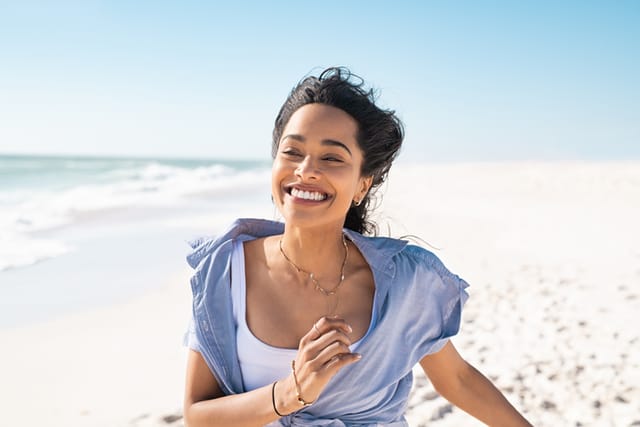 Happy smiling woman running on the beach.