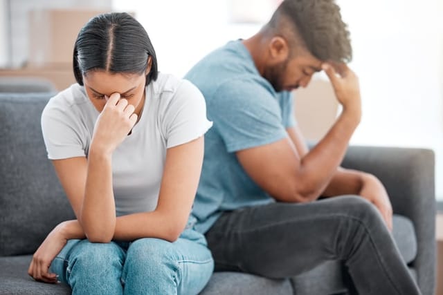 Young couple sitting on the sofa at home ignoring each other after a fight.