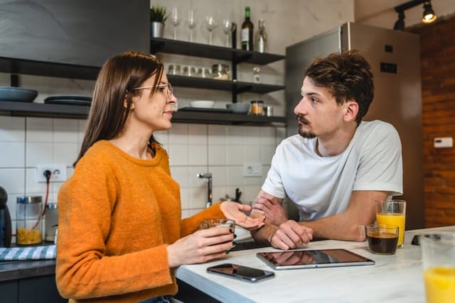 Couple in deep conversation in the kitchen.