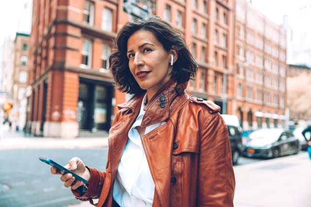Fashionable woman walking to the office on earphones.