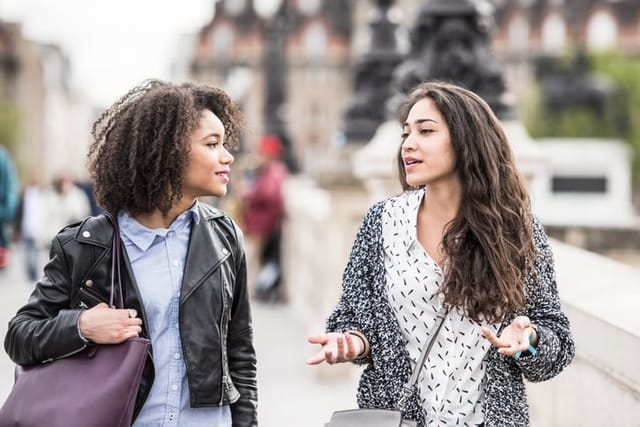 Two female friends talking outdoors.