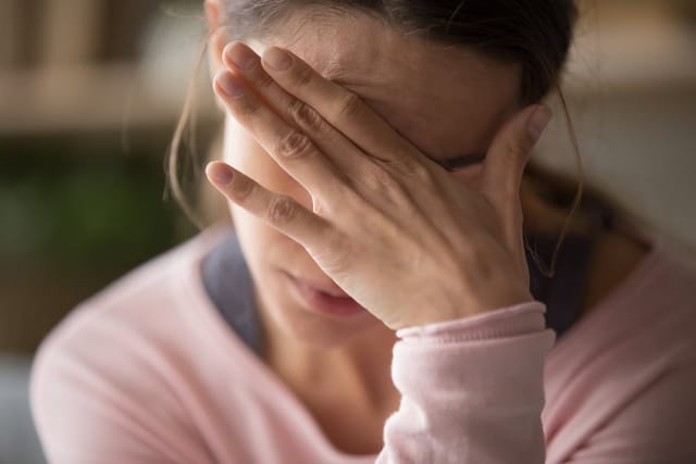 Tired woman with her hand over her eyes.