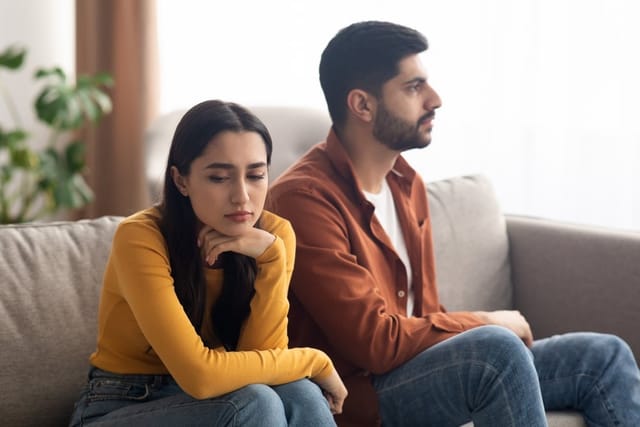 An unhappy couple having an argument on the sofa.
