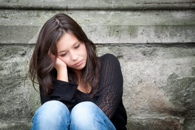 Young woman sitting alone outside.