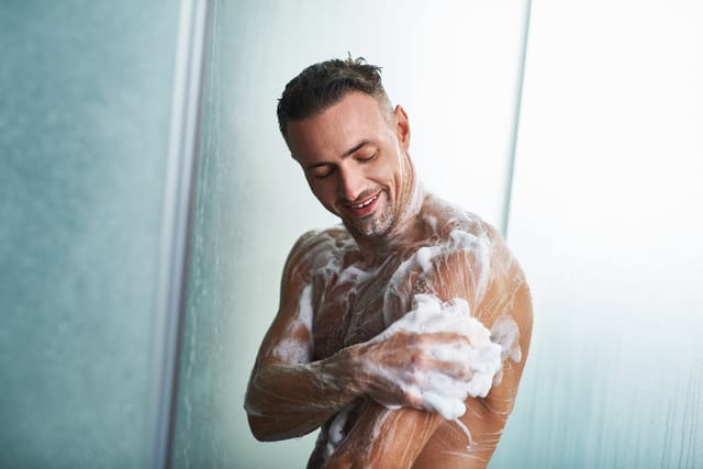 Man in the shower with soap.