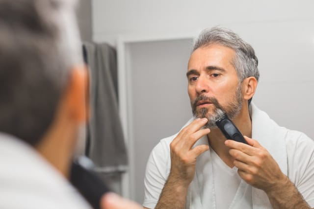 Man shaving in bathroom.