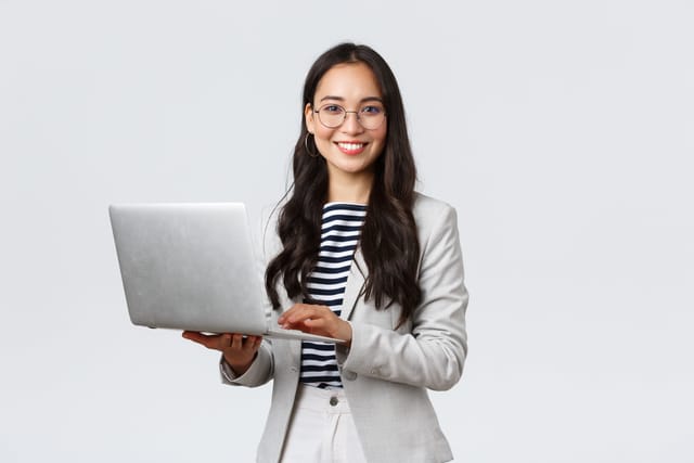 Woman holding a computer and looking confident.