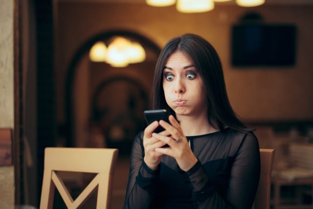 A woman looking confused while texting.