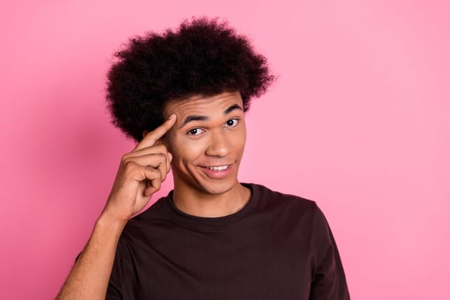 Handsome young man pointing at his head.