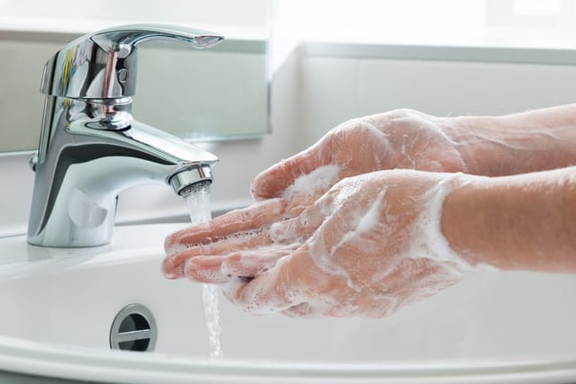 Woman washing hands at sink.