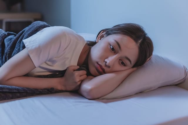 Woman laying in bed looking sad.