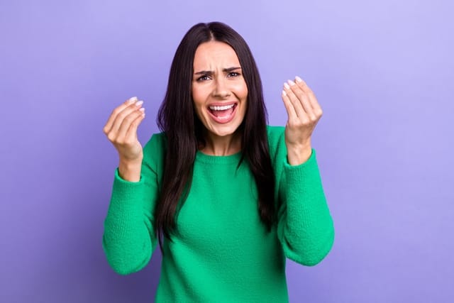 Woman holding her hands up looking angry.