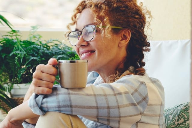 Woman smiling over a cup of coffee.