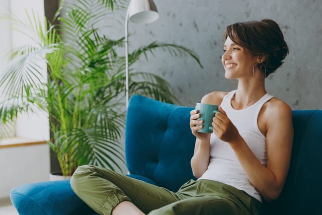 Young Woman sitting on sofa drinking tea.