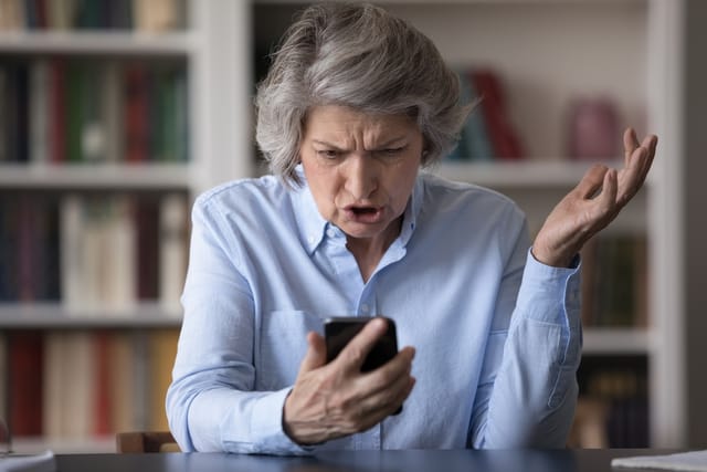 Older woman frustrated with her phone.