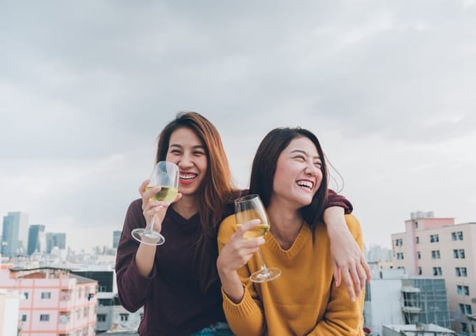 two friends drinking wine on rooftop