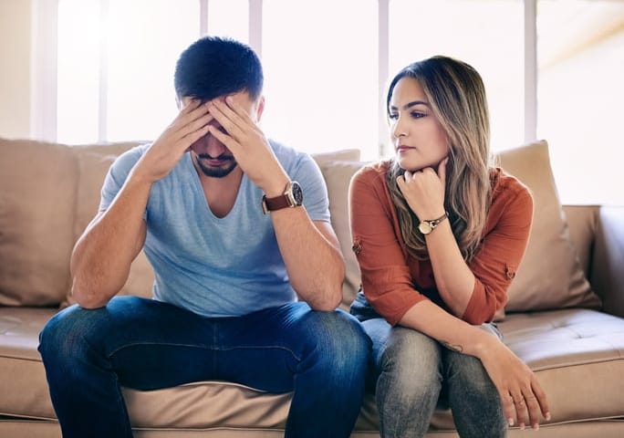 young couple sitting sofa unhappy