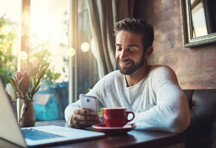 Cropped shot of a young man using his cellphone in a coffee shop