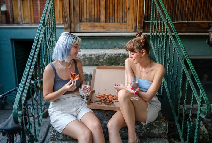 friends eating pizza on brownstone steps