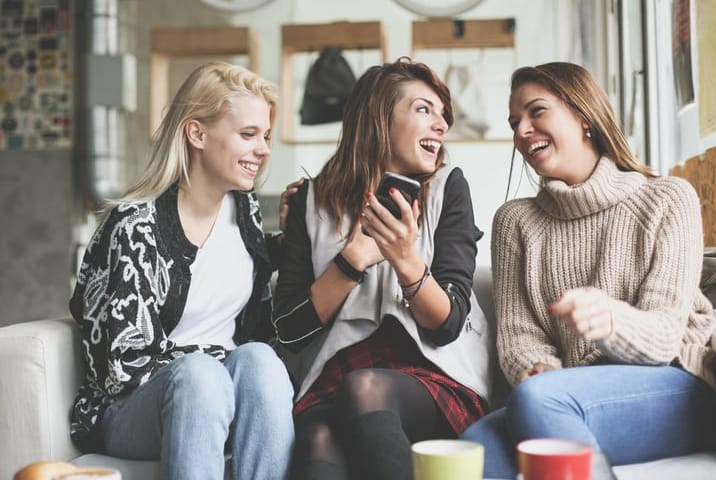 Friends using smart phone together at home.
