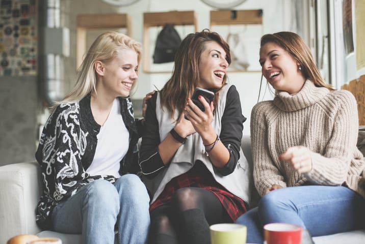 Friends using smart phone together at home.