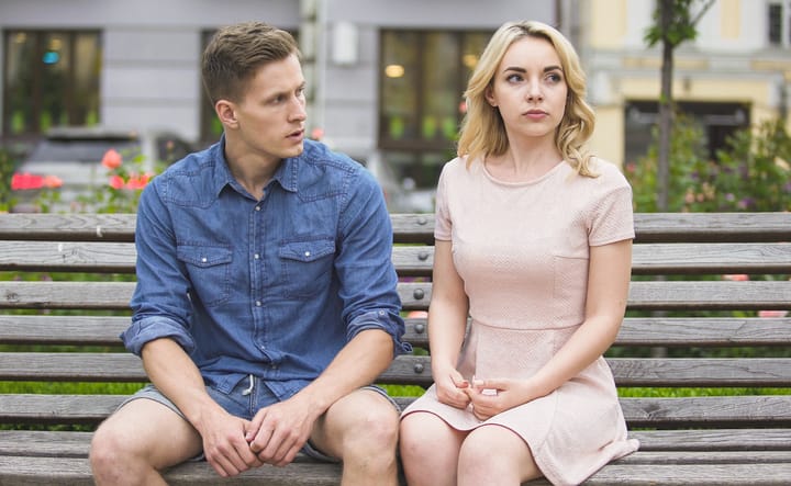 Man and woman breaking up on bench in park, conflict in relationship, problem