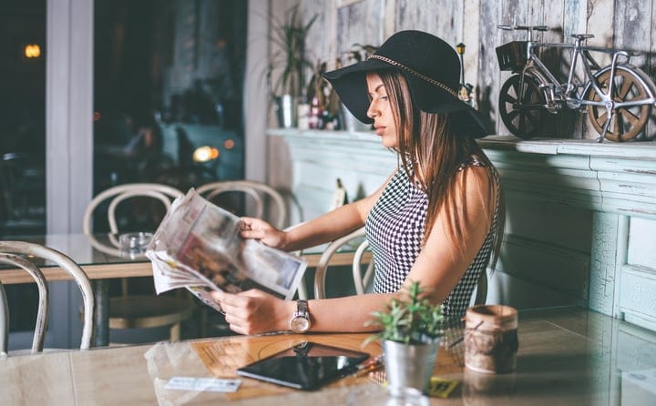 beautiful young woman with hat reading the newspapers