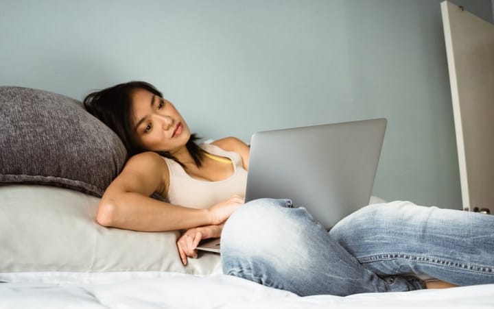 girl laid in bed with laptop