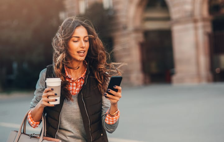 Woman surfing the net while drinking coffee outdoors.