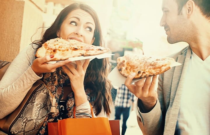 Couple eating pizza while walking.