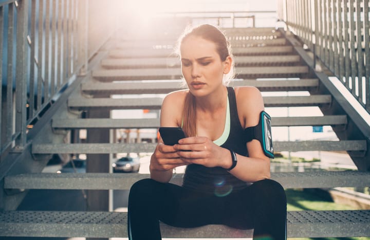 Sportswoman texting on a staircase.