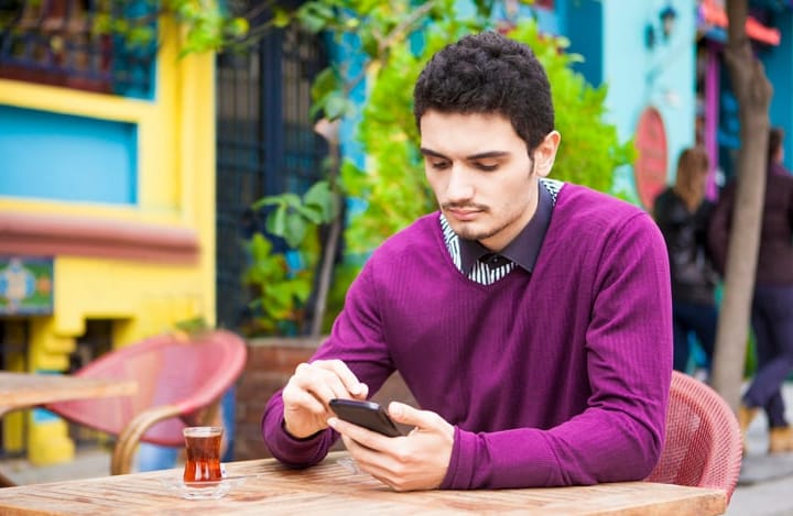 young man texting at a table