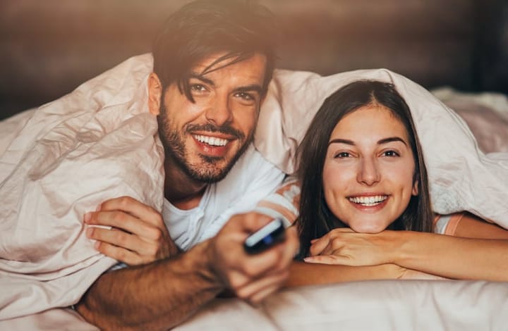 Couple watching TV in bed.