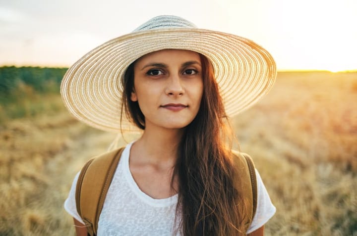 Girl with straw hat in the meadow field.