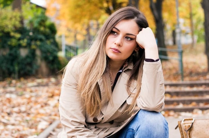 sad woman sitting in autumn leaves