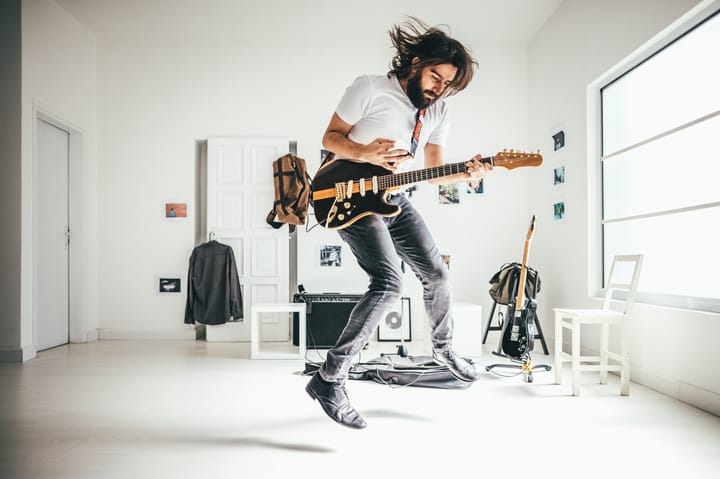 guy playing guitar in white room