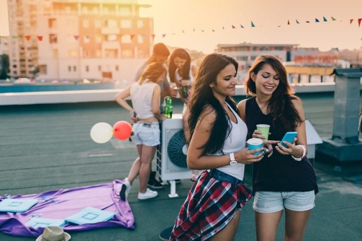 female friends reading texts at rooftop party