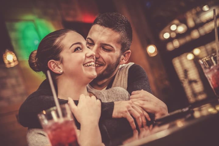 Couple in bar laughing and embracing in a bar