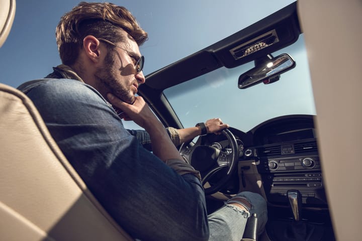 Below view of a pensive man driving a convertible car.