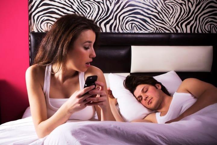Couple in bed girl checking phone