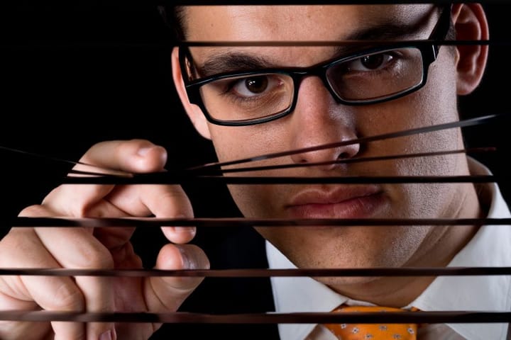Guy peering through blinds