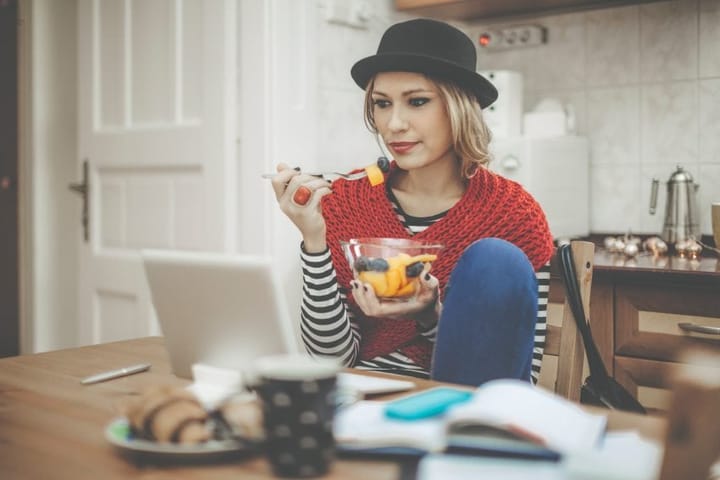 Hipster girl eating fruit at table