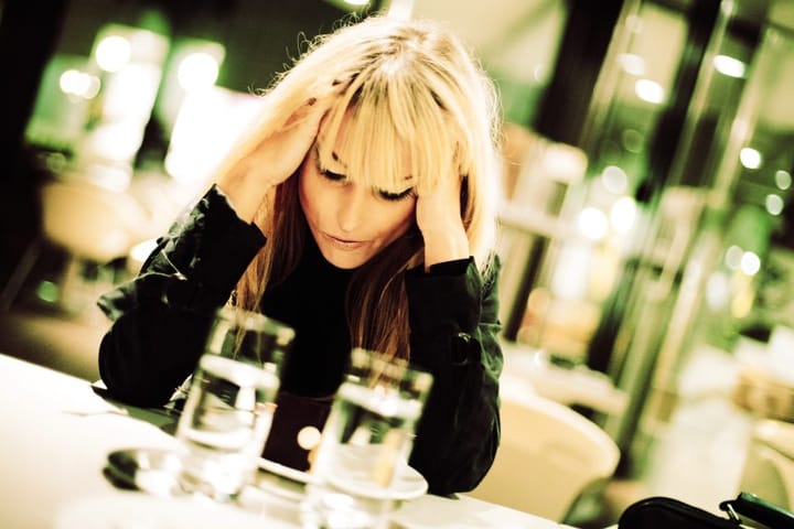 Blonde woman sat at table perplexed
